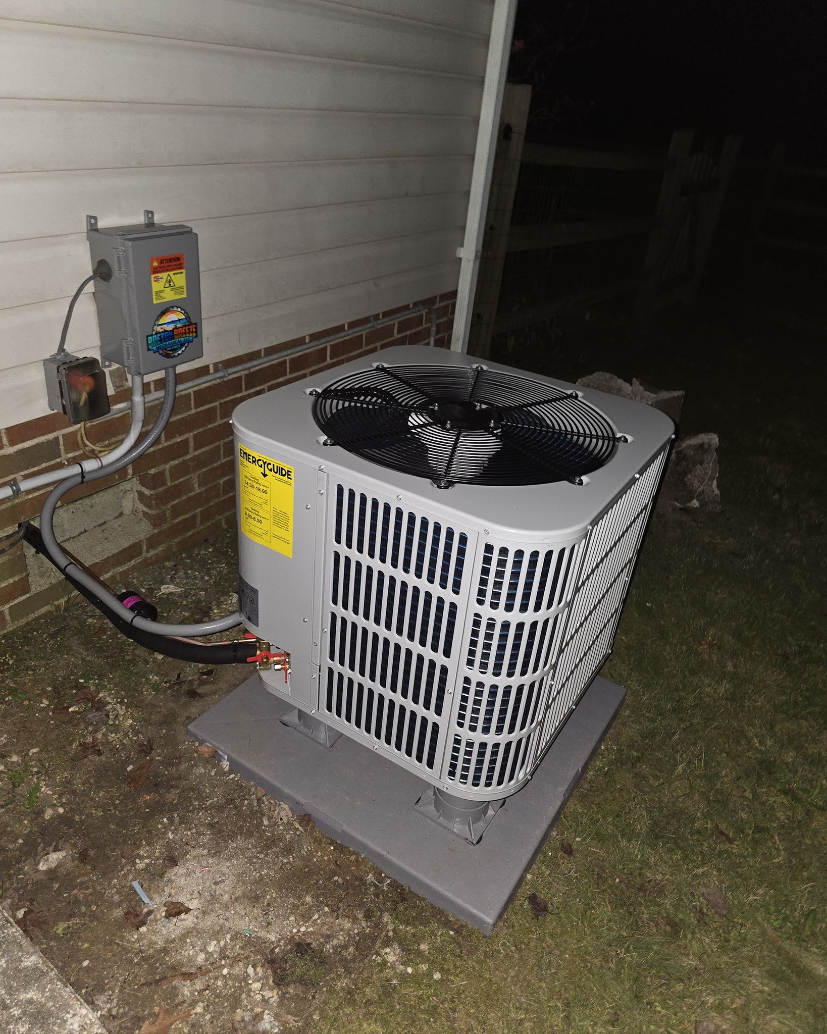 Exterior air conditioning unit next to a wall with electrical box.