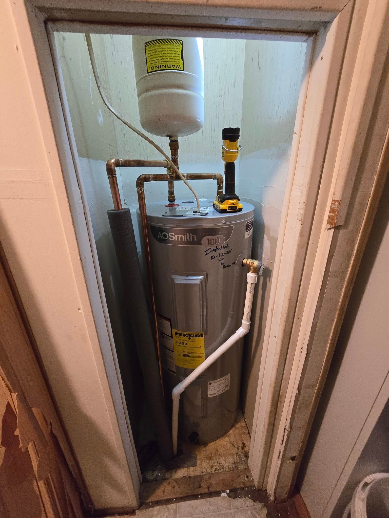 Water heater in a utility closet with an expansion tank above. Gray, white, copper pipes.