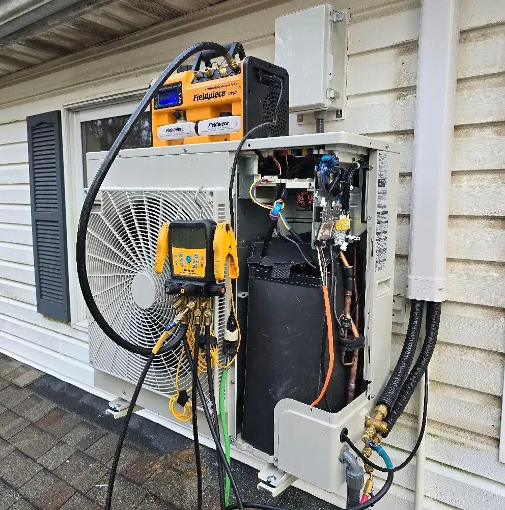 Person in blue shirt repairing an outdoor air conditioning unit.