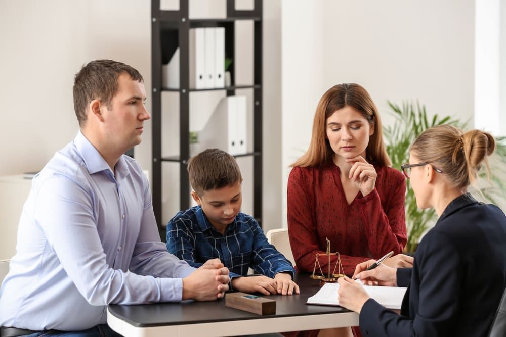 A Family Is Sitting At A Table Talking To A Lawyer — Adamson Legal & Conveyancing in Wingham, NSW