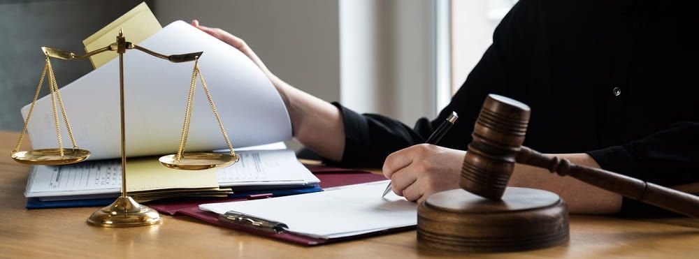A Judge Is Sitting At A Table With A Gavel And Scales Of Justice — Adamson Legal & Conveyancing in Wingham, NSW