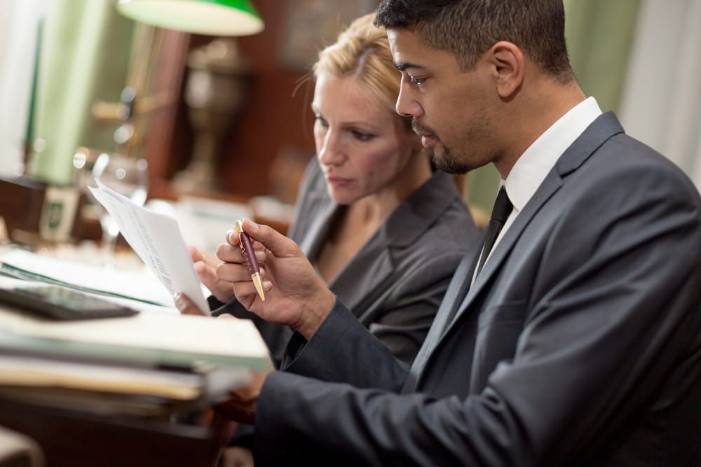 A Man And A Woman Are Looking At A Piece Of Paper — Adamson Legal & Conveyancing in Wingham, NSW