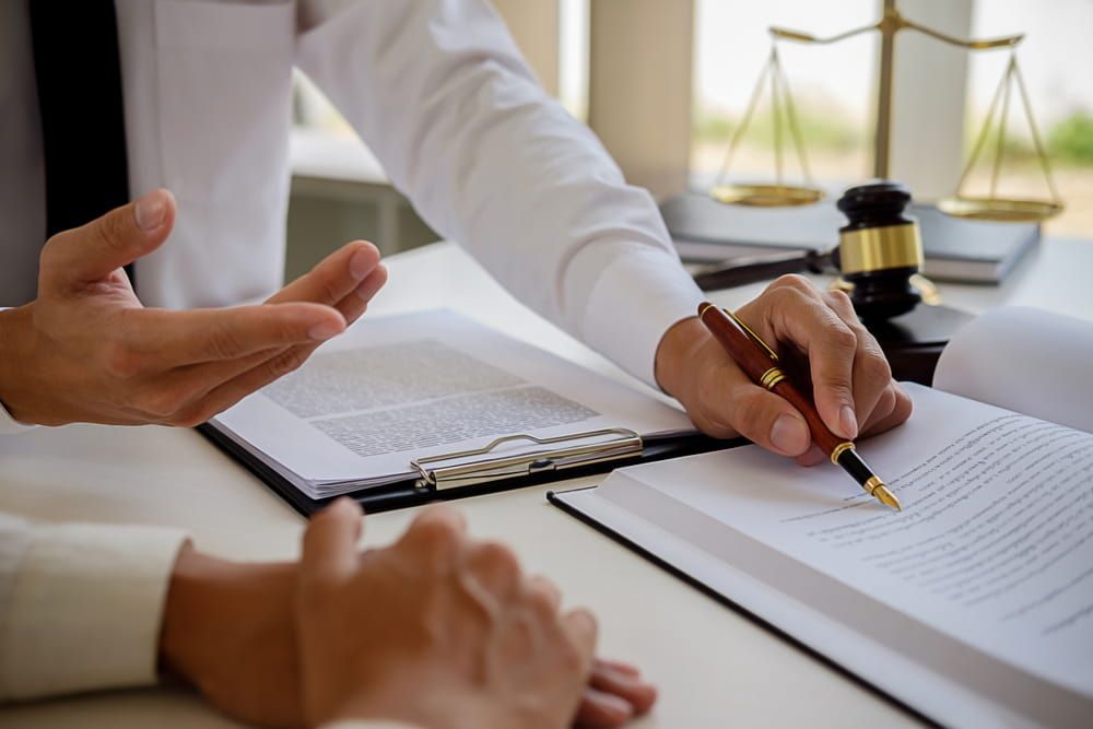A Man Is Writing On A Piece Of Paper With A Pen — Adamson Legal & Conveyancing in Wingham, NSW
