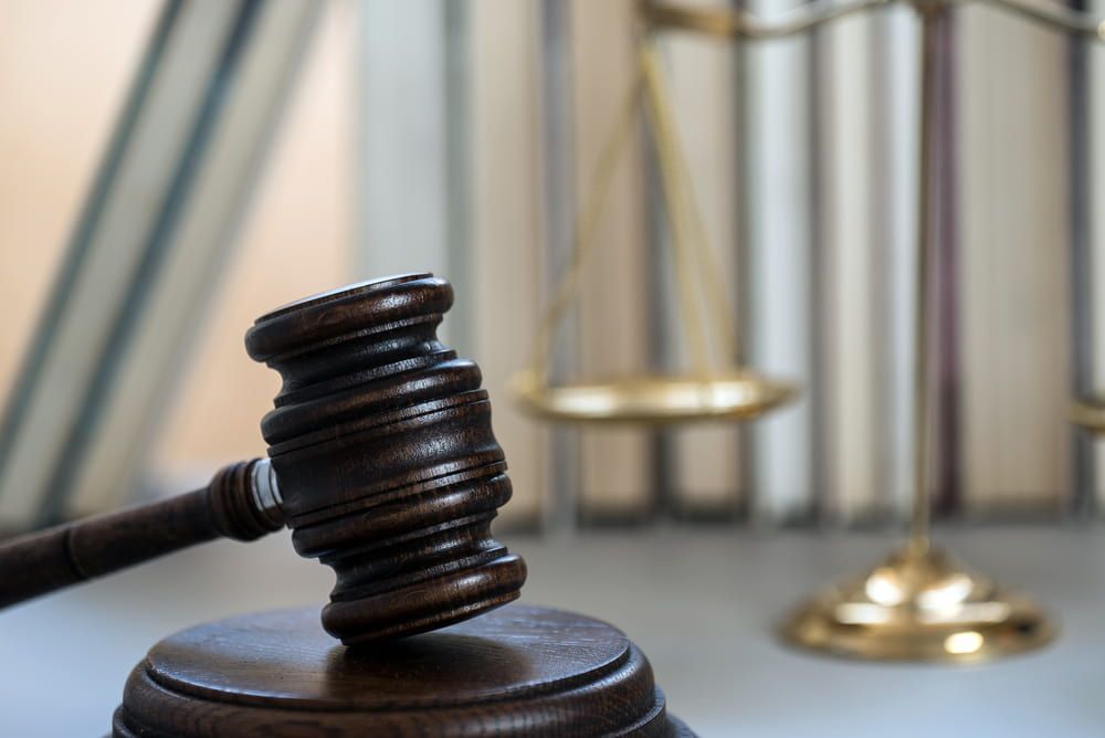 A Wooden Judge 's Gavel Is Sitting On A Table In Front Of A Scale Of Justice — Adamson Legal & Conveyancing in Wingham, NSW