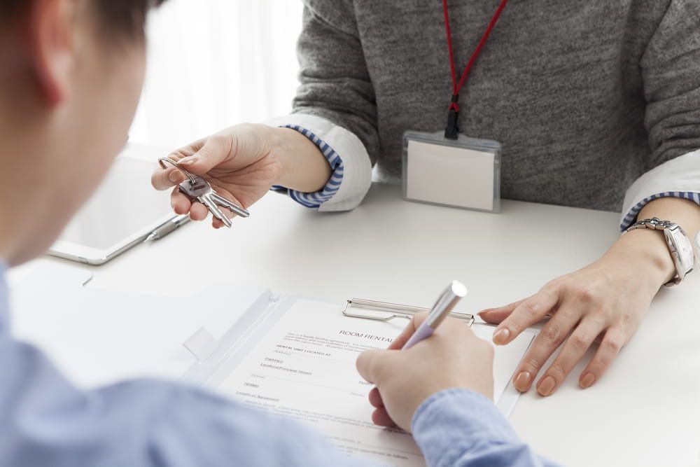 A Man Is Sitting At A Table Talking To A Woman Who Is Writing On A Piece Of Paper — Adamson Legal & Conveyancing in Wingham, NSW