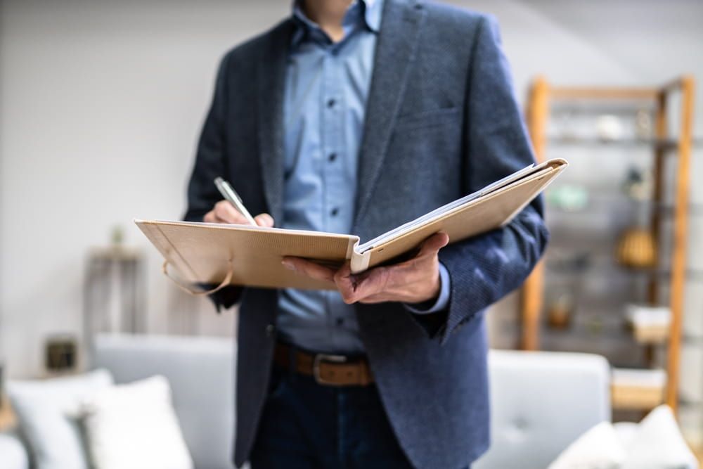 A Man In A Suit Is Holding A Clipboard And Writing On It  — Adamson Legal & Conveyancing in Wingham, NSW