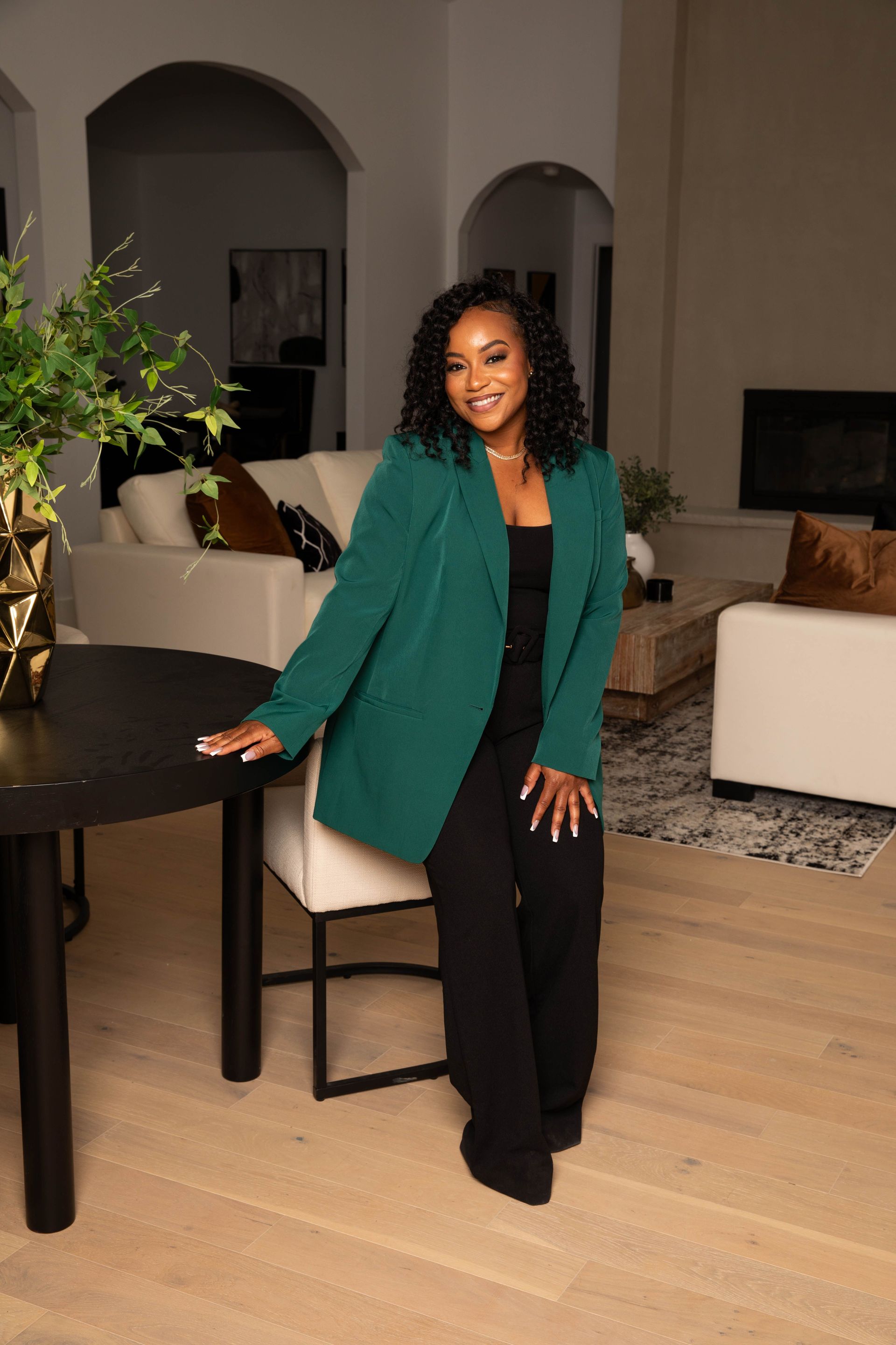 A woman is sitting at a desk with a laptop and a vase of flowers.