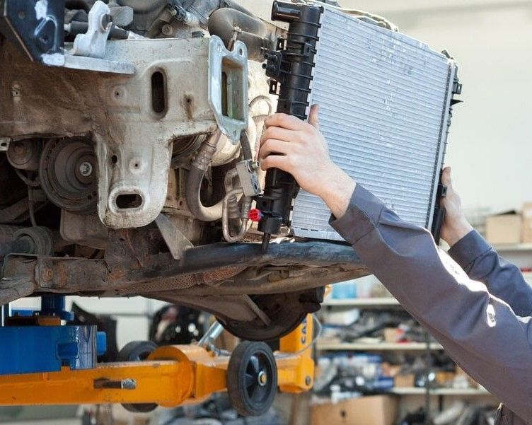 A Mechanic is Fixing a Radiator on a Car in a Garage — Radiator Doctor In Pialba, QLD
