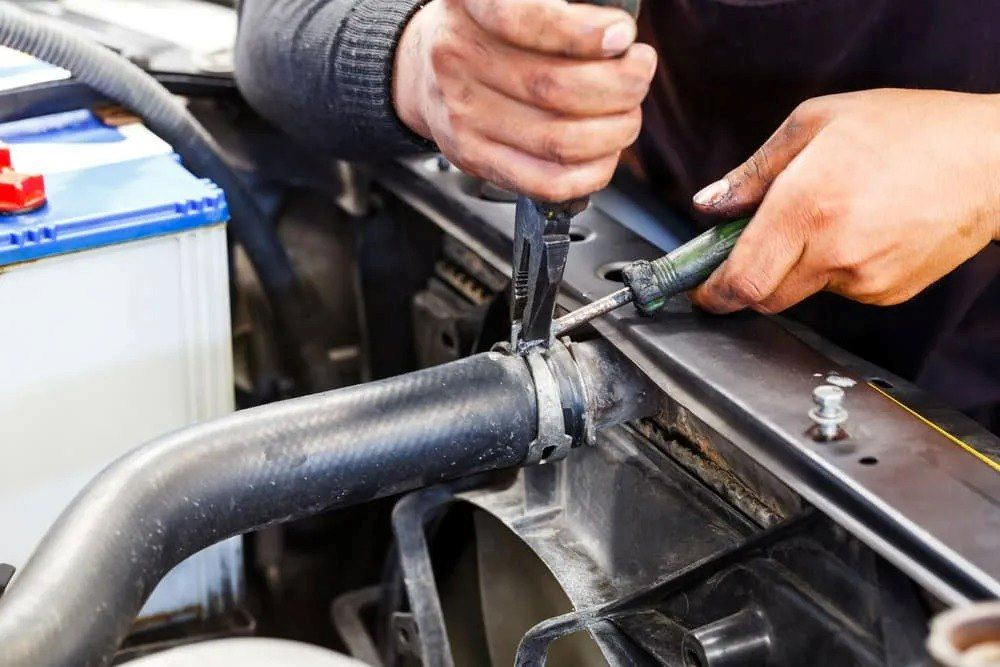 A Man Is Working on A Car Radiator with A Screwdriver — Radiator Doctor In Pialba, QLD