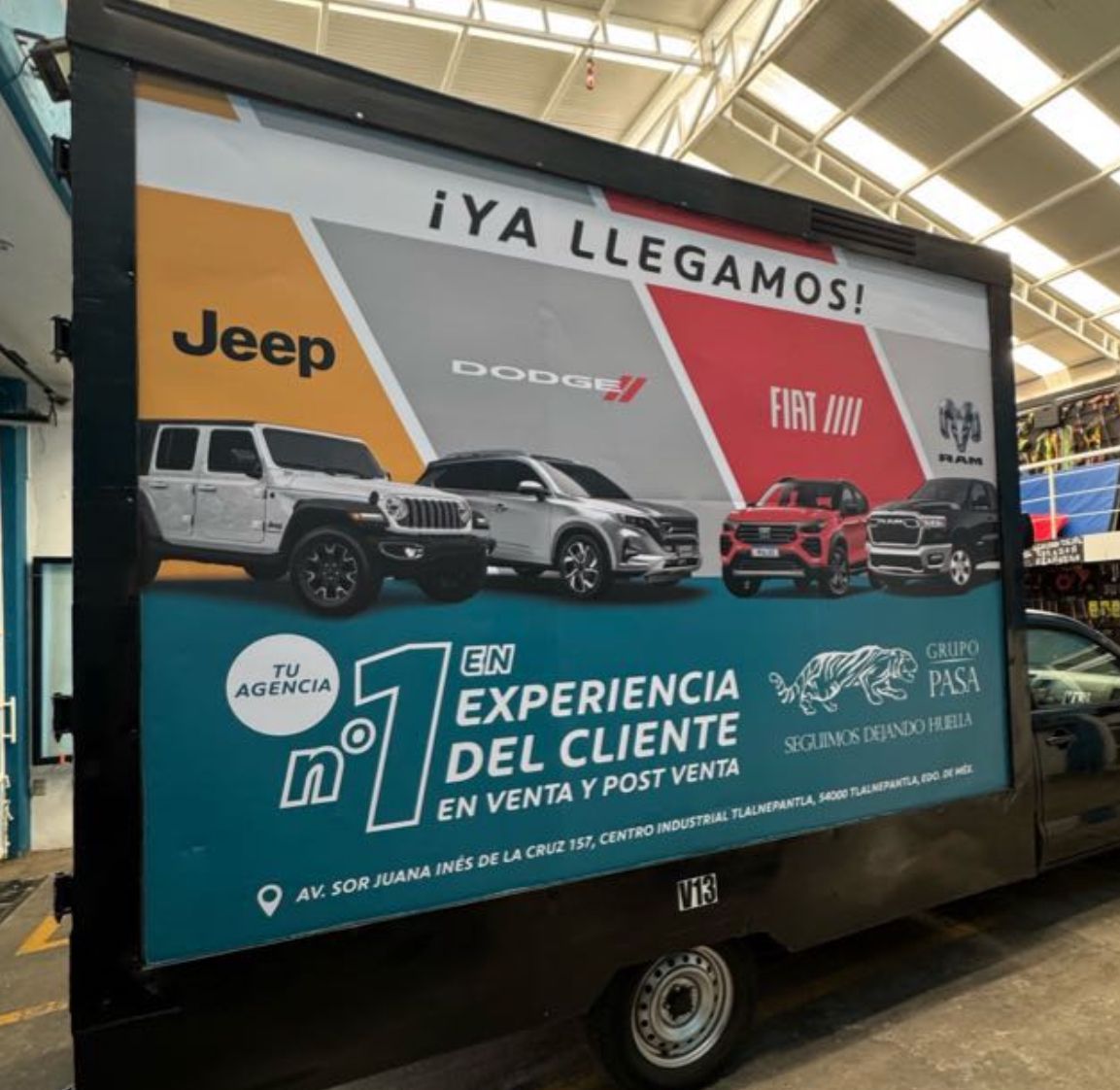 Anuncio en cartelera móvil de Jeep, Dodge y Fiat que presenta automóviles, un mensaje sobre la experiencia del cliente y la ubicación.