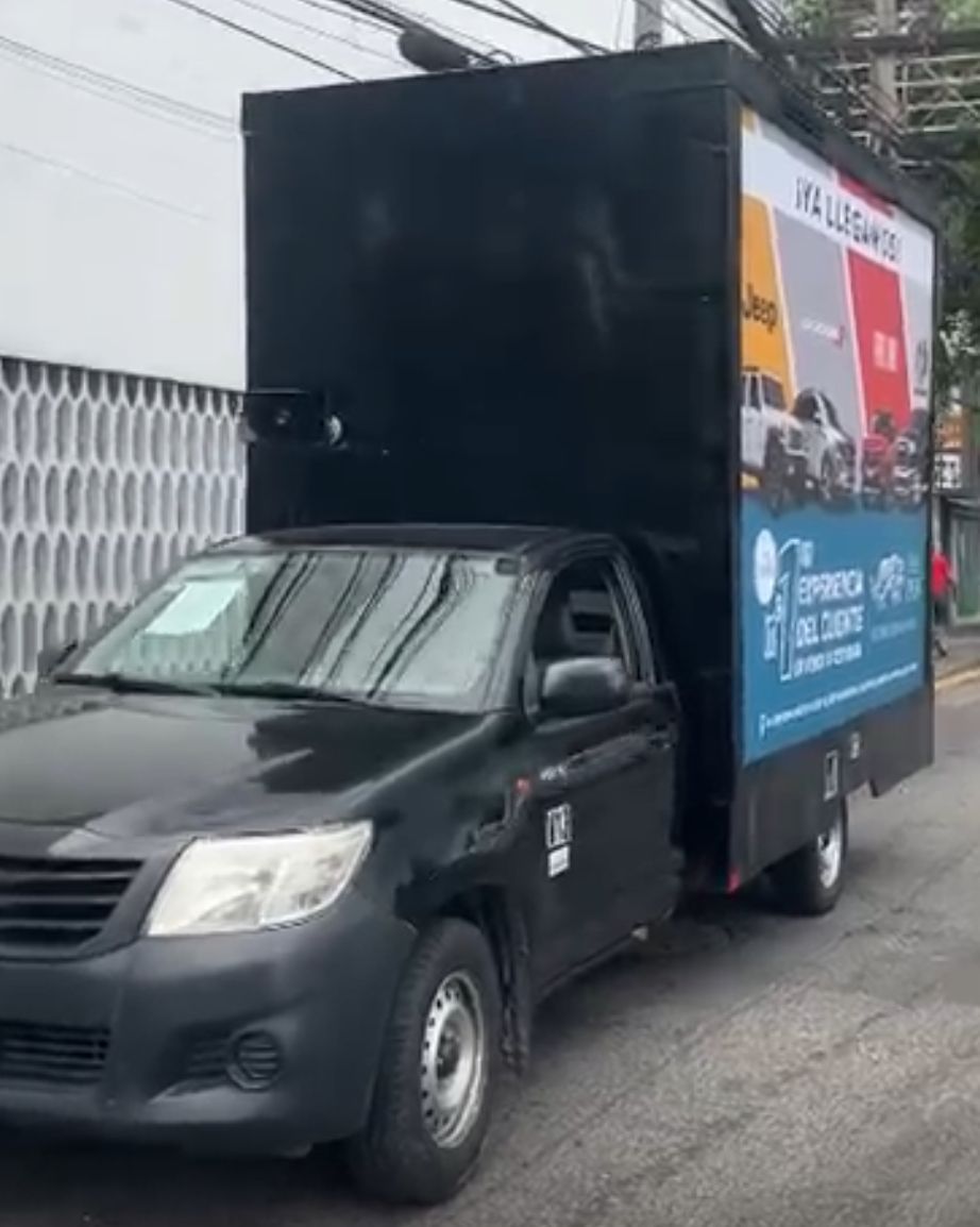 Camioneta negra con una gran caja negra en la parte trasera que muestra un anuncio.