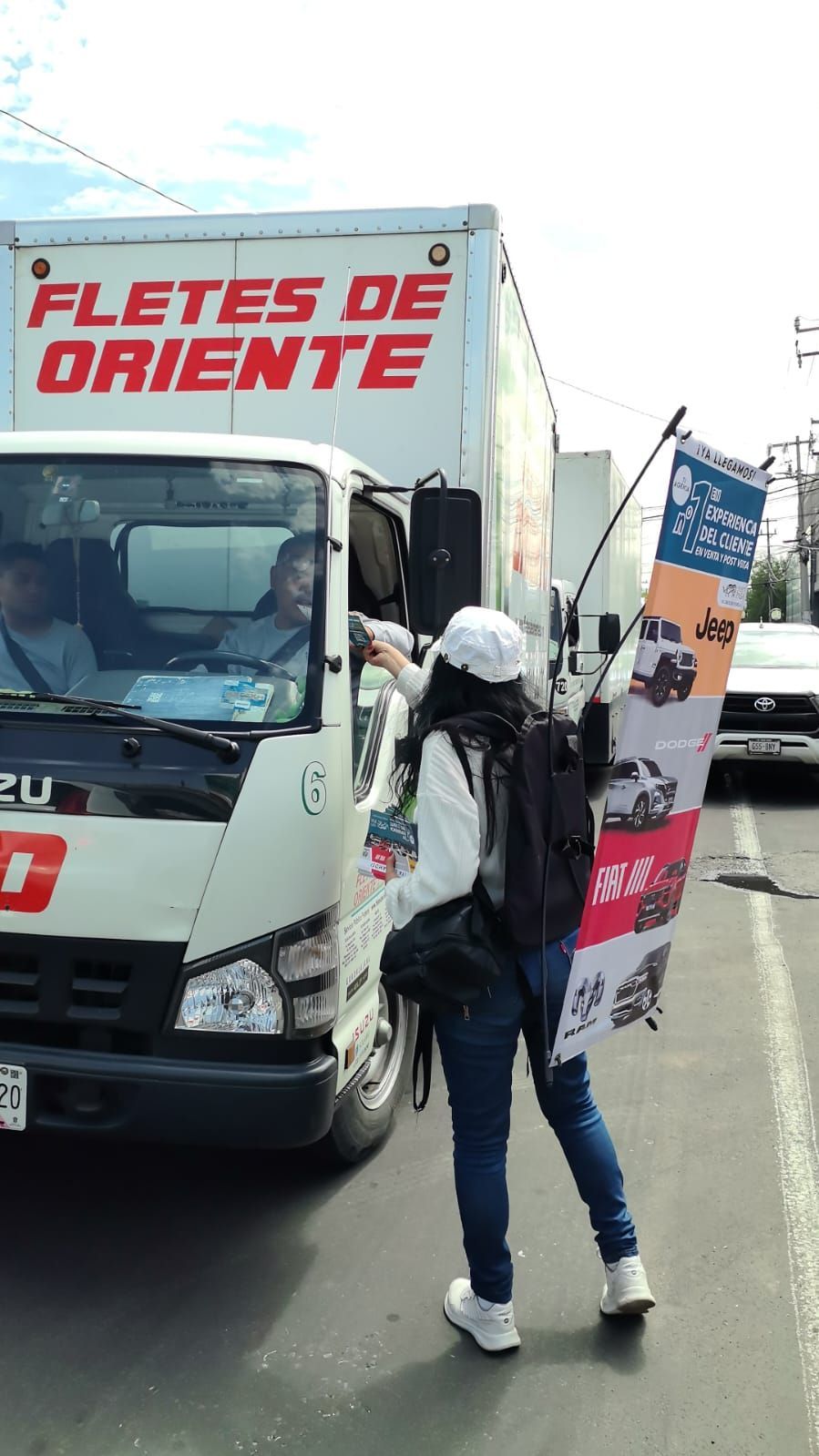 Persona entregando un volante a un camionero. El camión tiene la inscripción