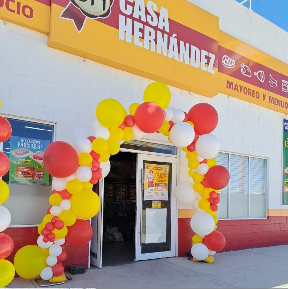 Entrada de la tienda Casa Hernández decorada con globos, amarillos y rojos, dando la bienvenida a los compradores.
