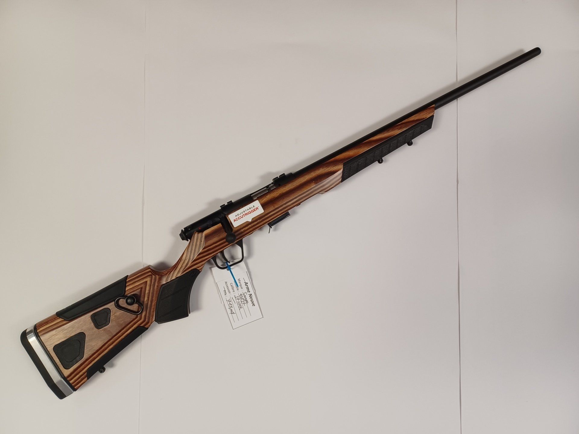 Fusil avec une crosse en bois et à motifs noirs sur fond blanc.