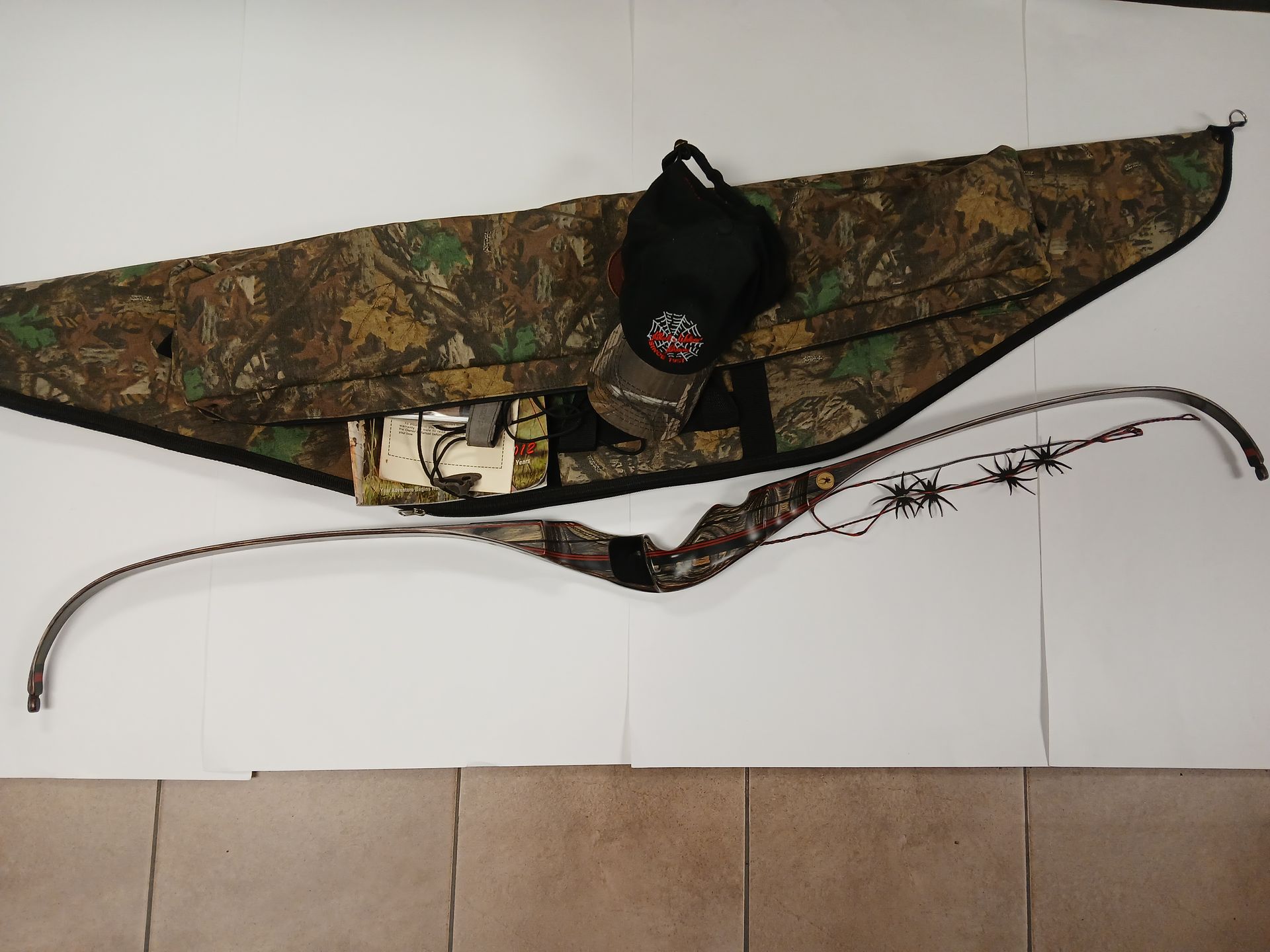 Arc recourbé camouflage, étui et chapeau sur une surface de couleur claire.