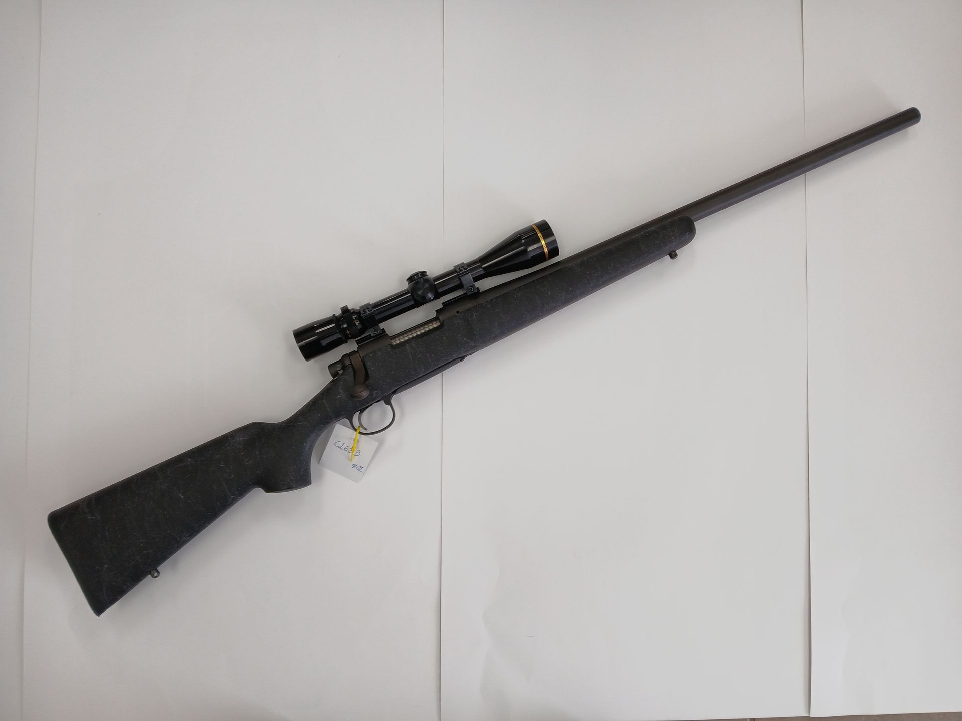 Fusil noir avec une lunette sur une surface blanche.