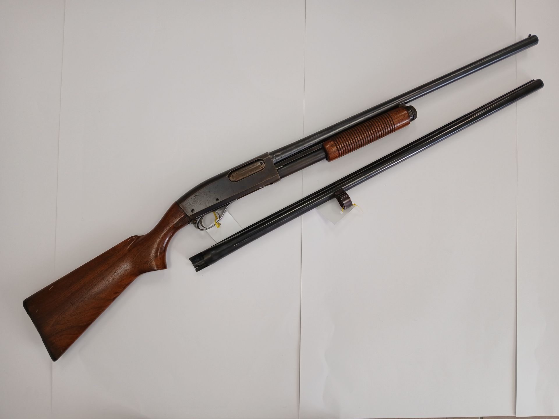 Fusil de chasse à deux canons sur une surface blanche.