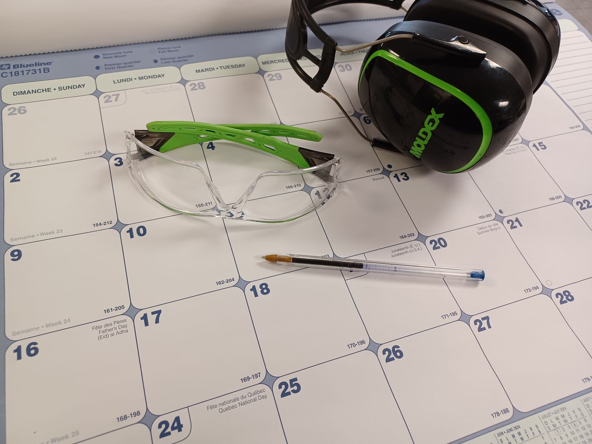 Safety glasses, headphones, and pen on a large calendar.