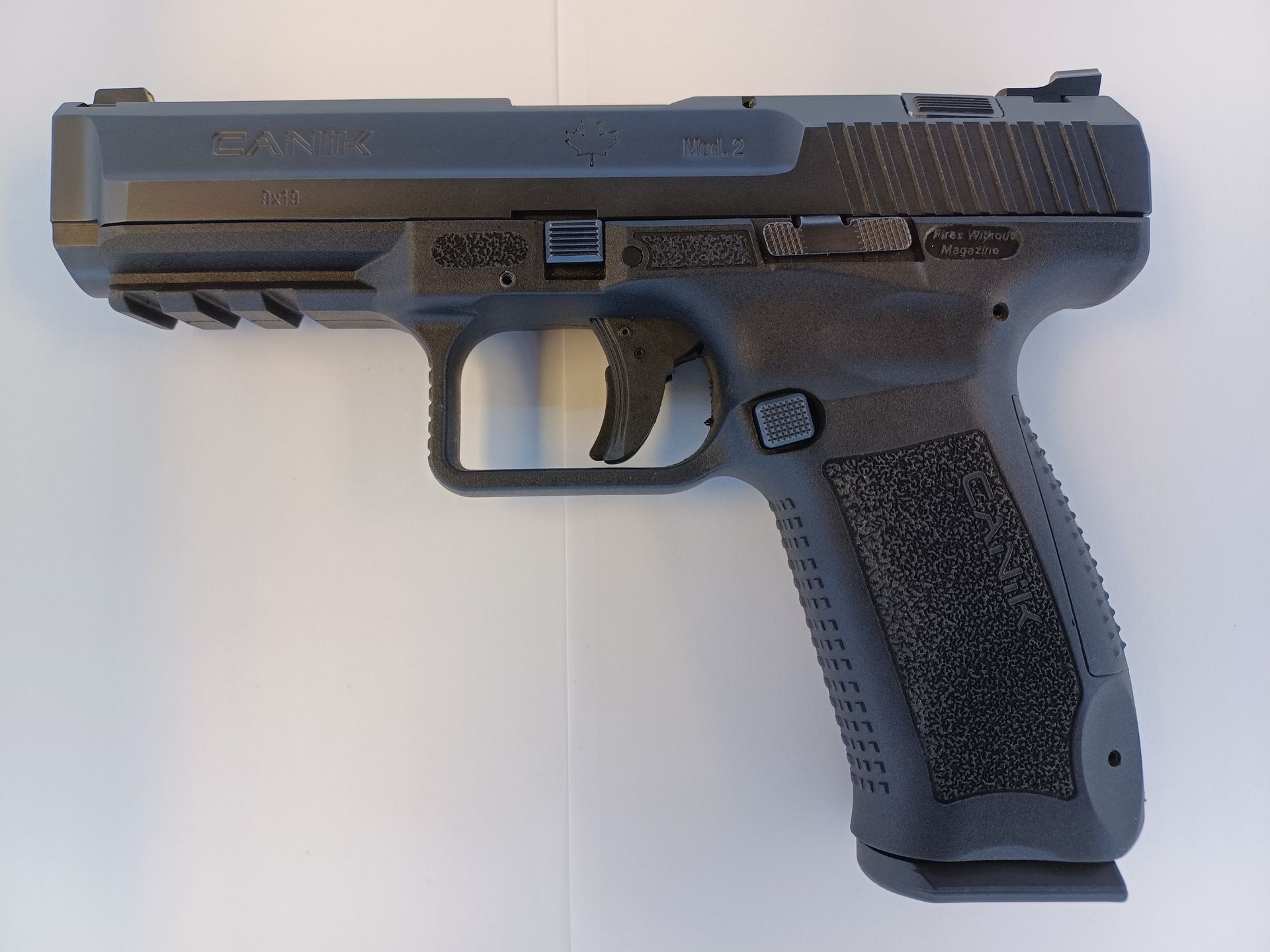 Black semi-automatic handgun on a white surface, showing the side profile.