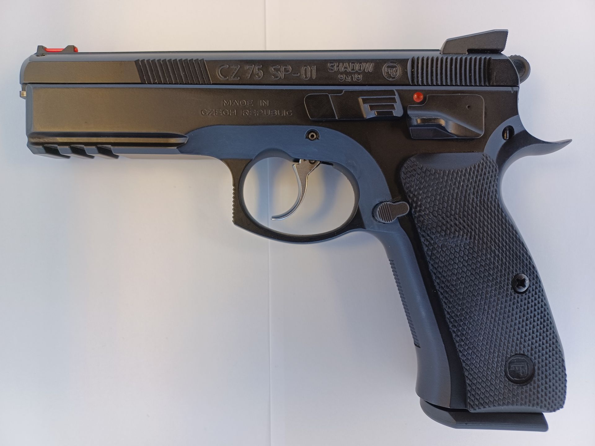 Black semi-automatic pistol with a red front sight, against a white background.