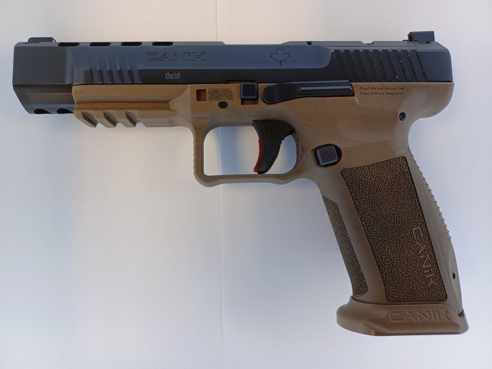 Tan and black handgun on a white surface.