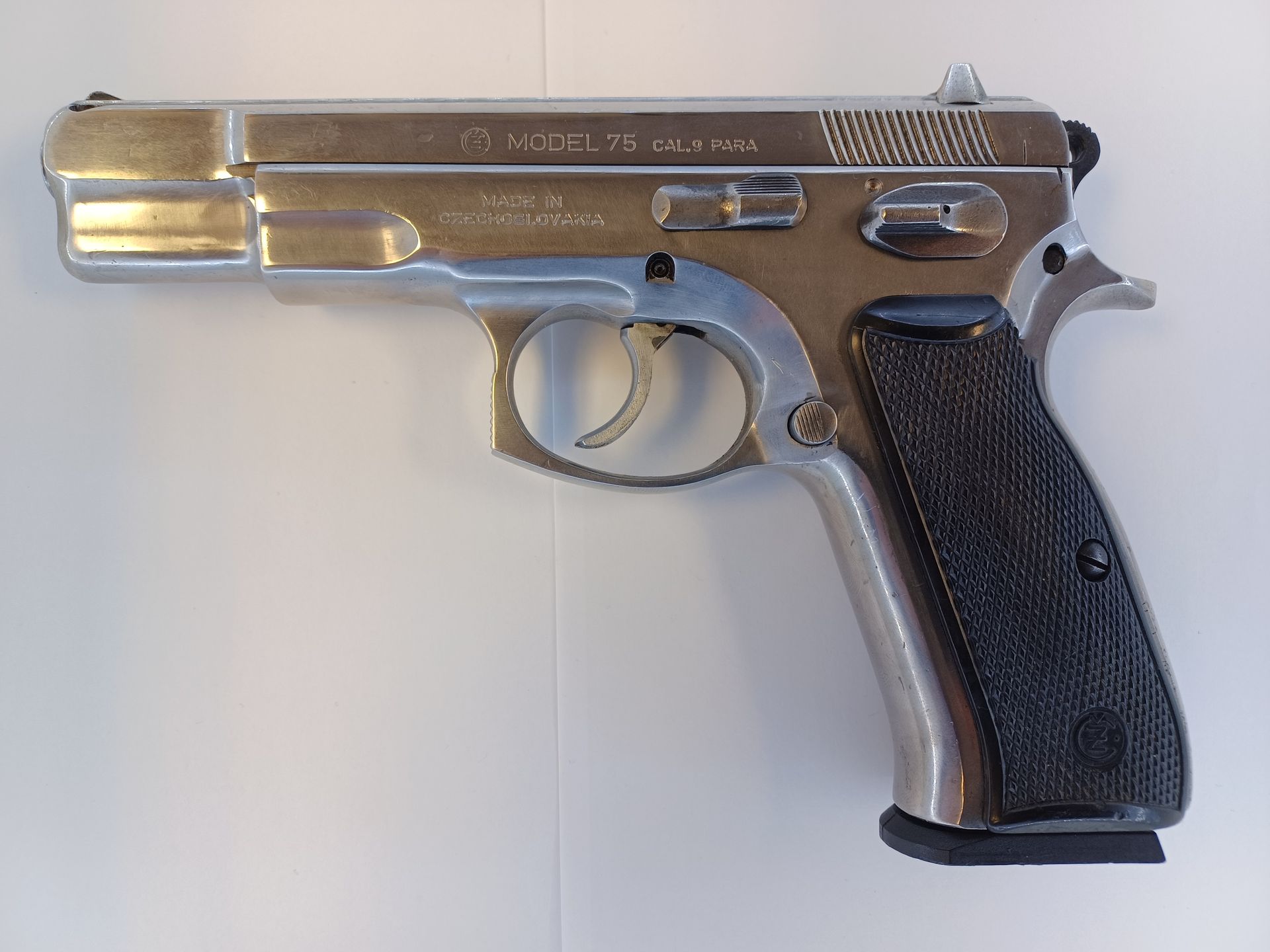 Shiny silver handgun with black grip on a white surface.