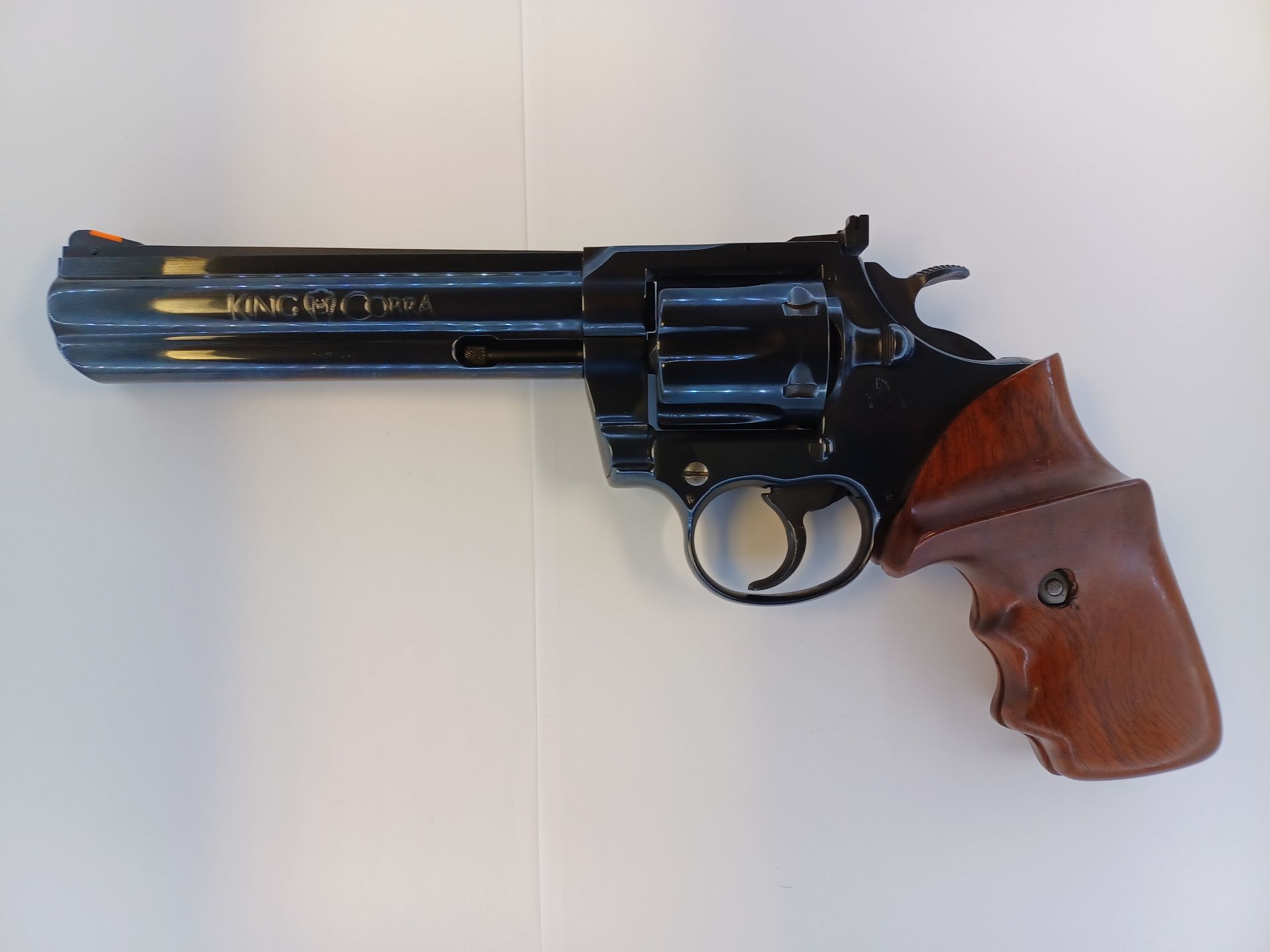Revolver with a wooden handle, resting on a white surface.