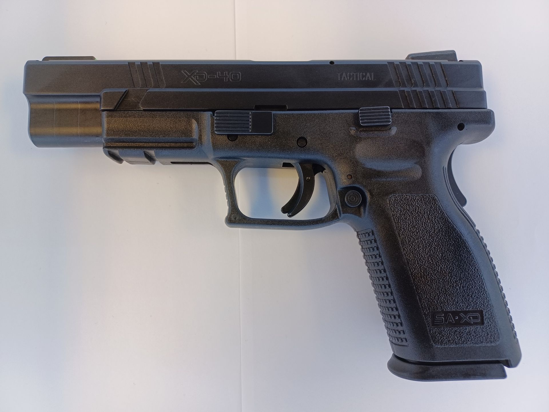 Black handgun on a white surface, right side view.