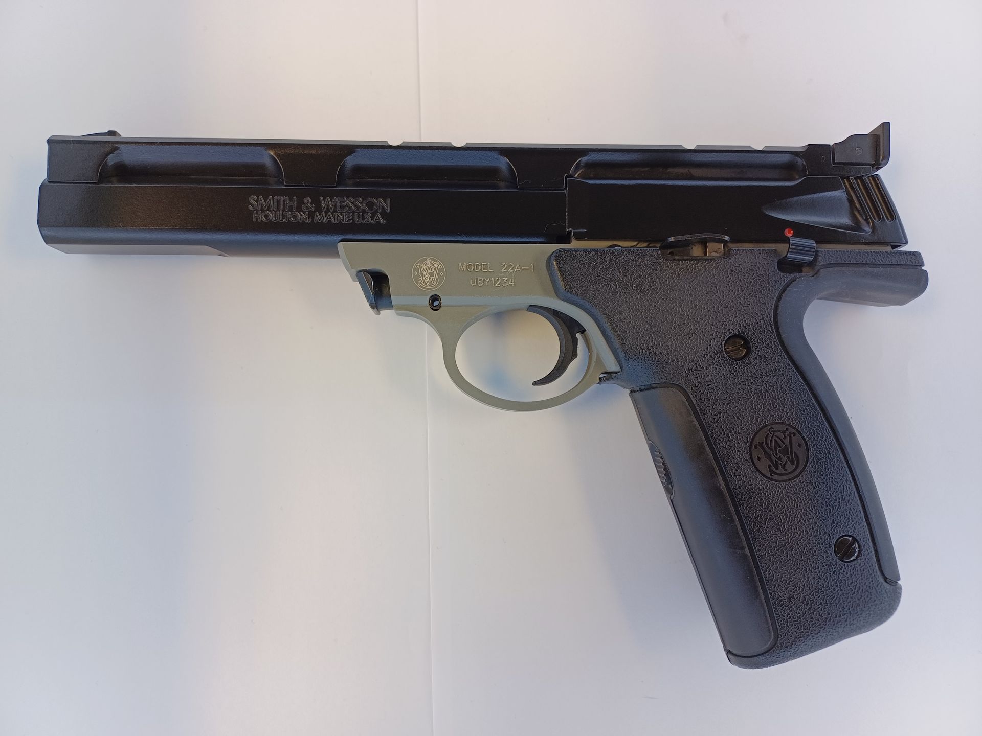 Black and green Smith & Wesson semi-automatic pistol on a white surface.