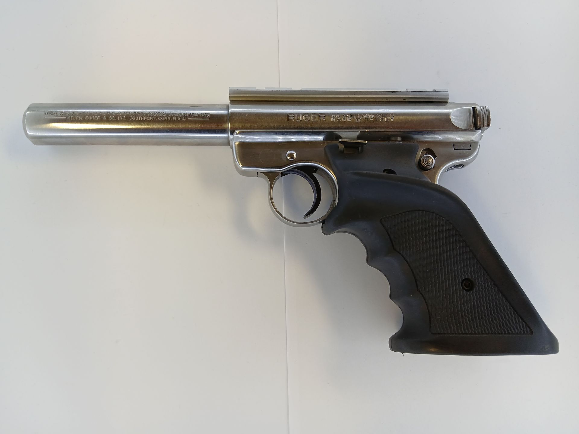 Pneumatic air pistol, silver metal with a black textured grip, on a white surface.