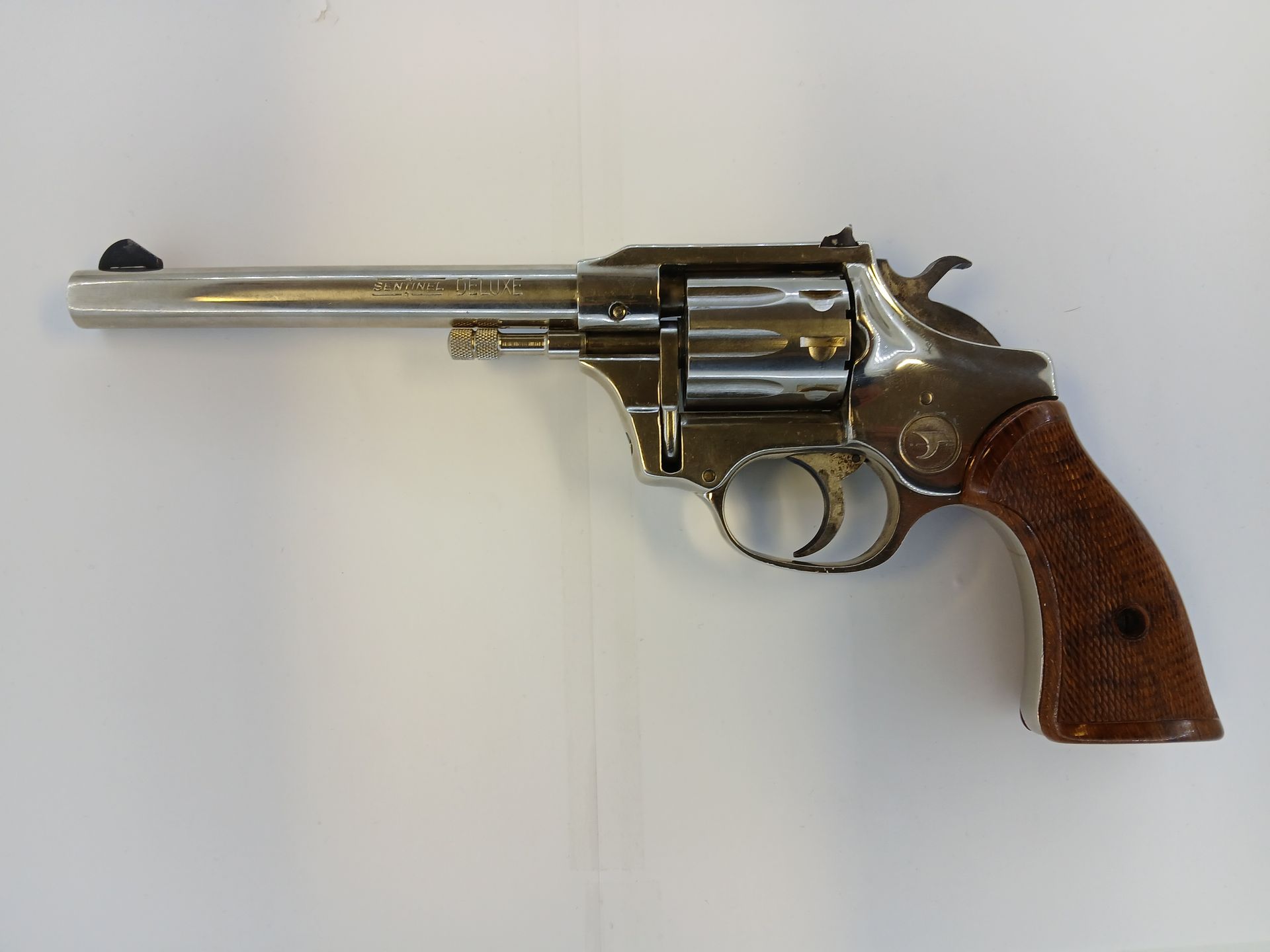 Silver revolver with brown grip on a white surface.