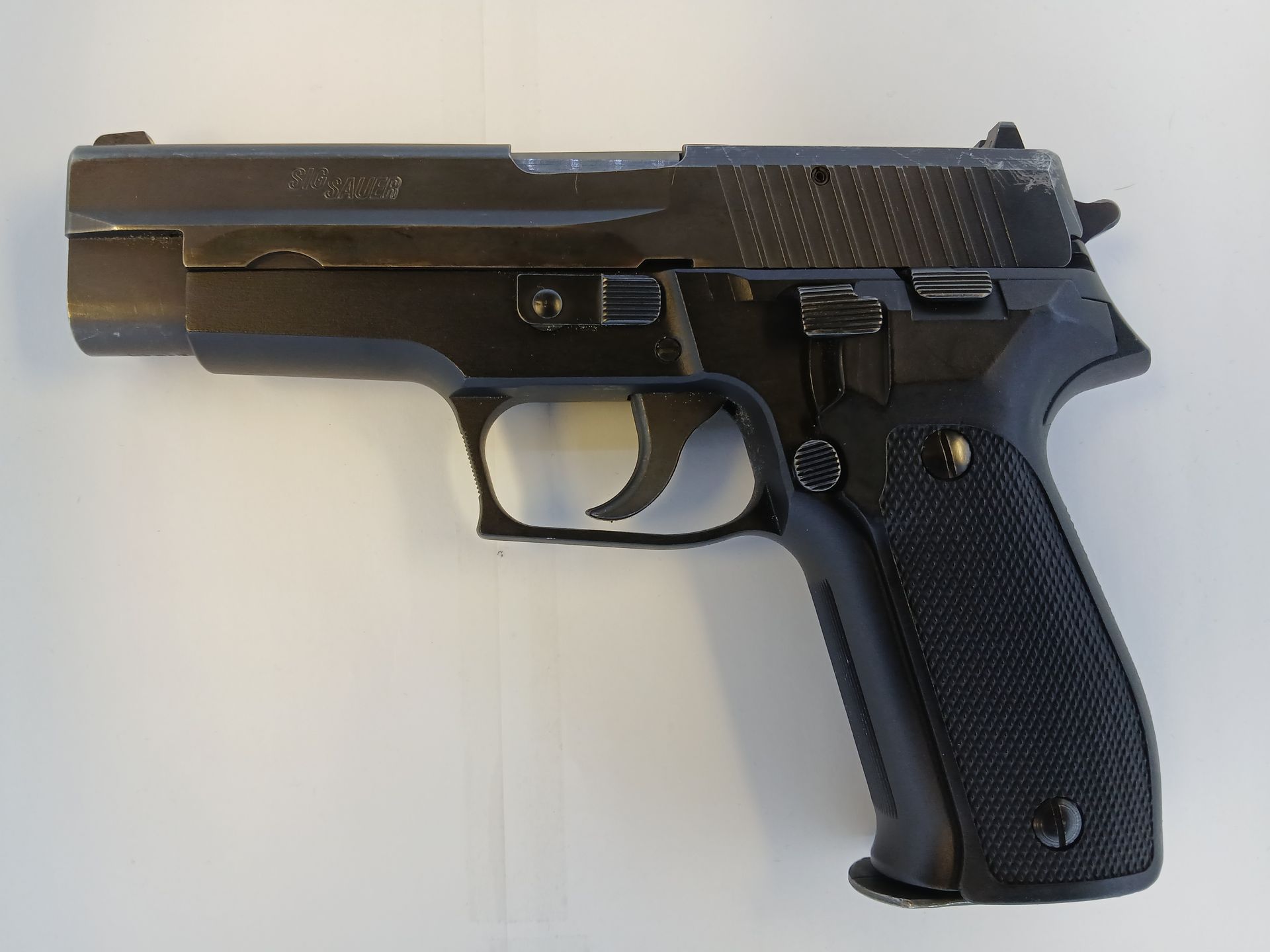 Black handgun, side view, on a white surface.