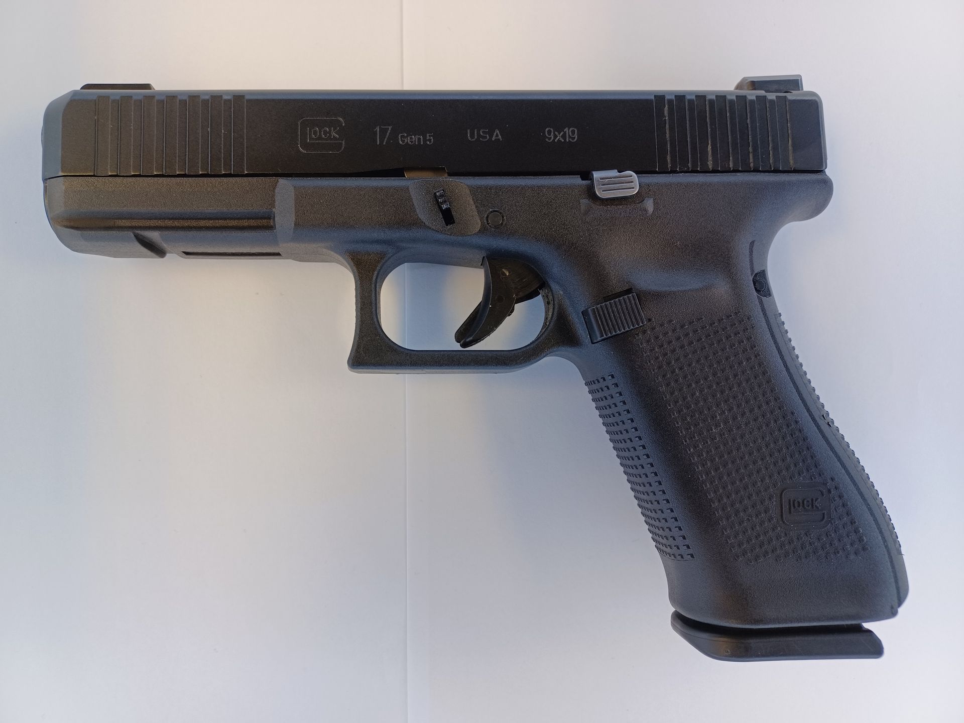 Black Glock handgun on a white surface.