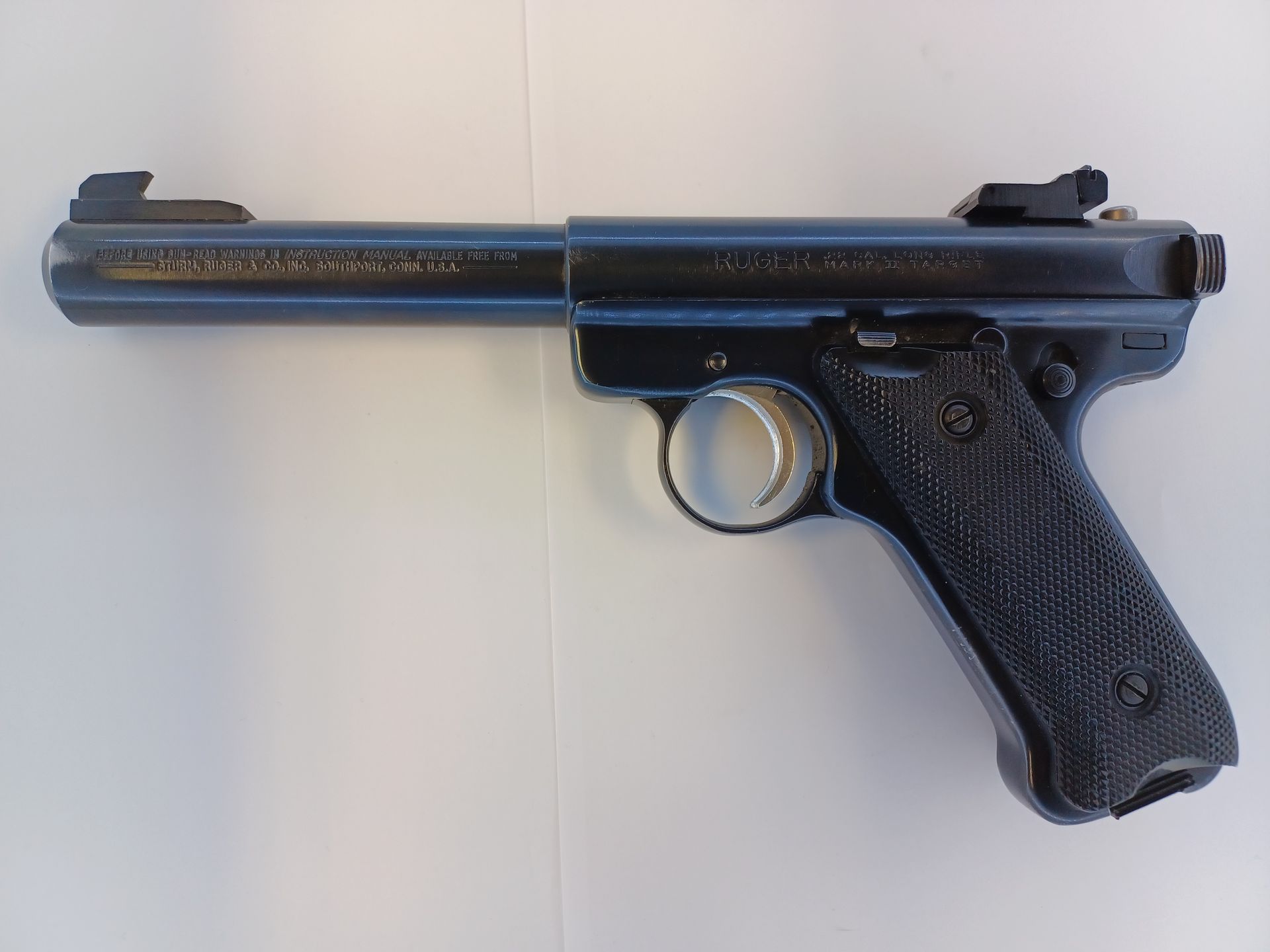 Blue handgun with a long barrel, set on a white surface.