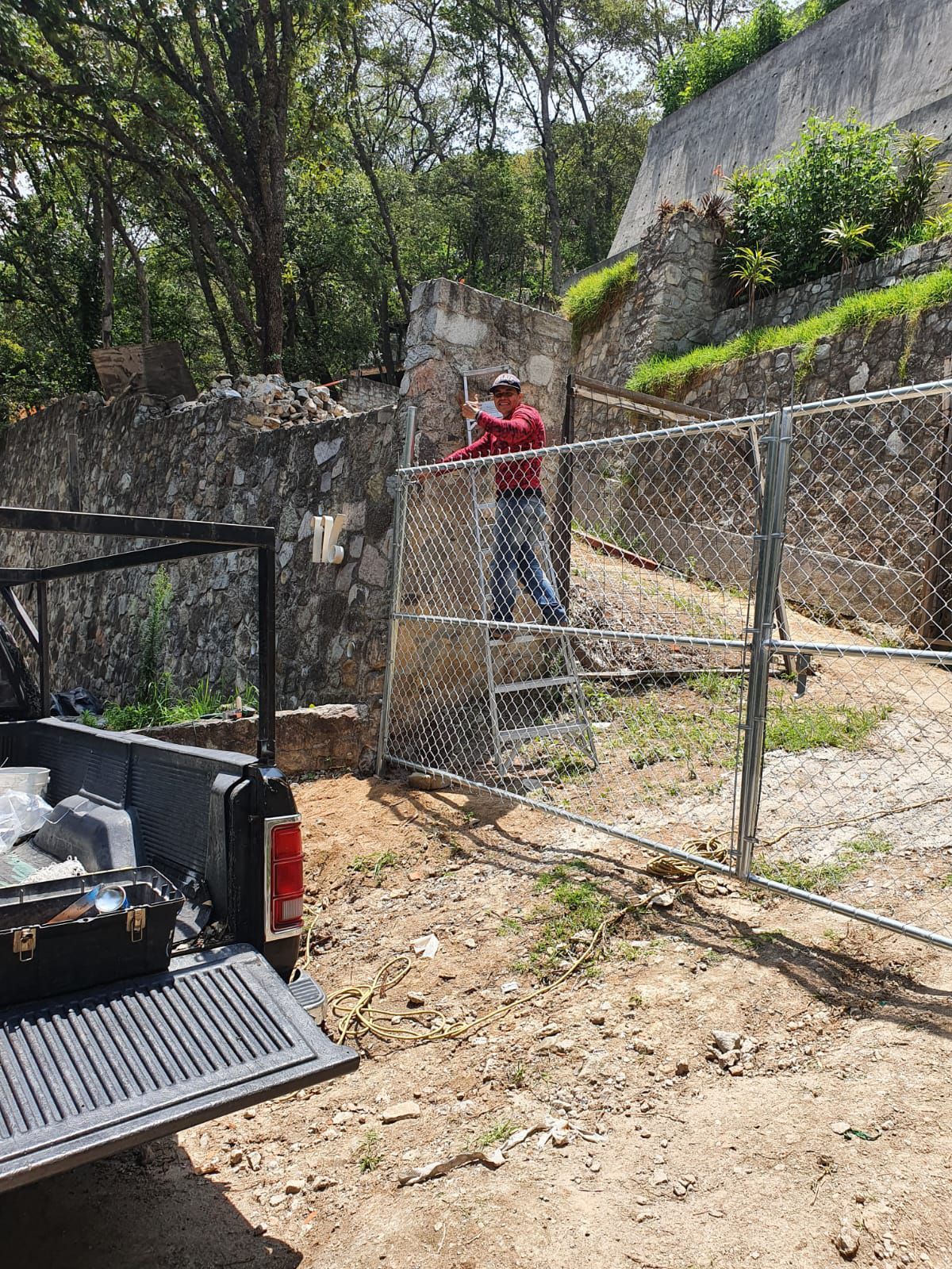 Un hombre está parado detrás de una cerca de alambre al lado de un camión.