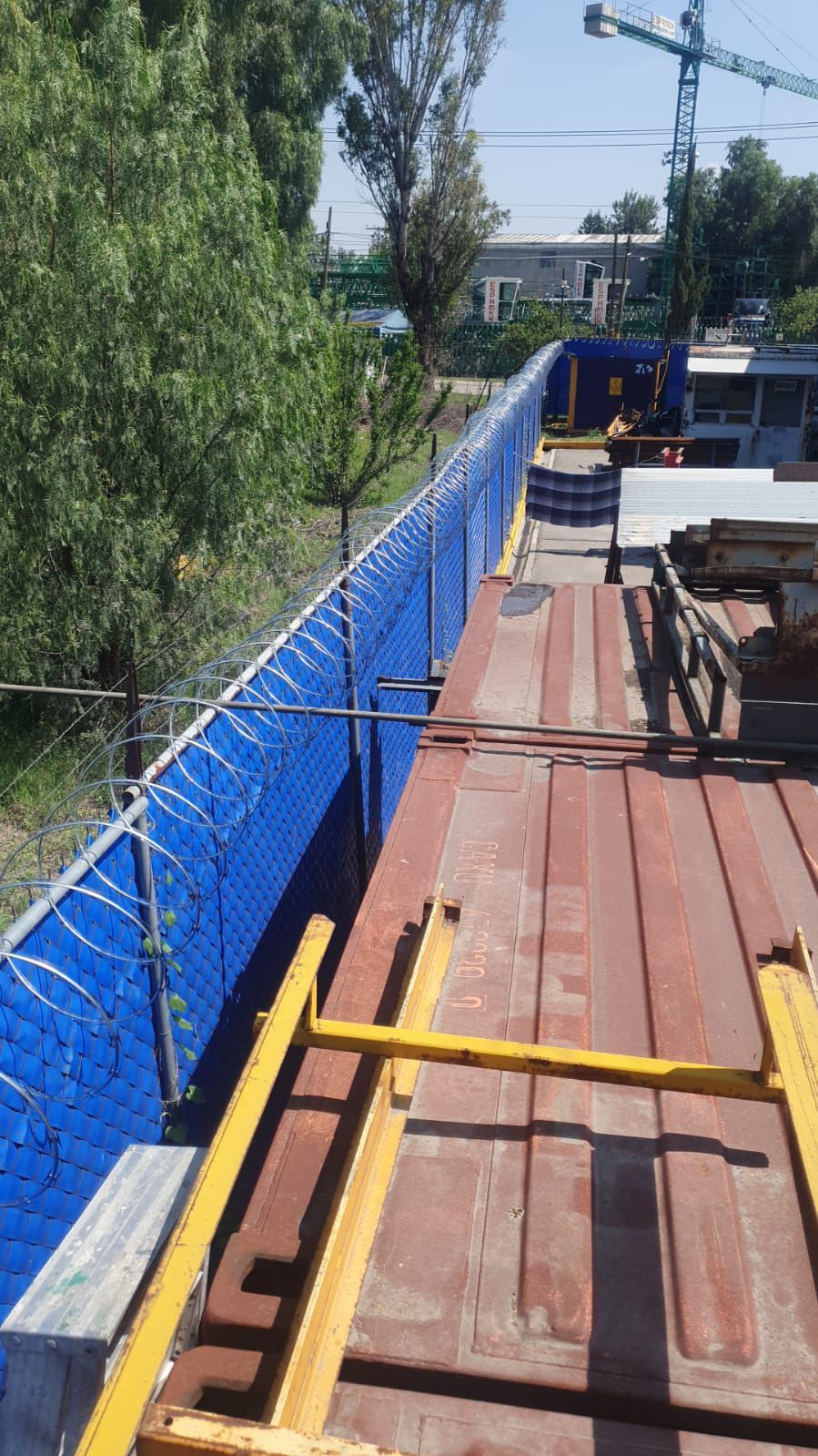 Una terraza de madera con una valla de alambre de púas detrás.