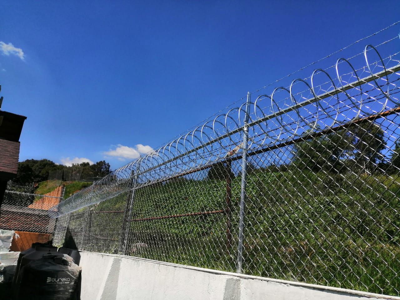 Una valla de alambre de púas con un cielo azul al fondo