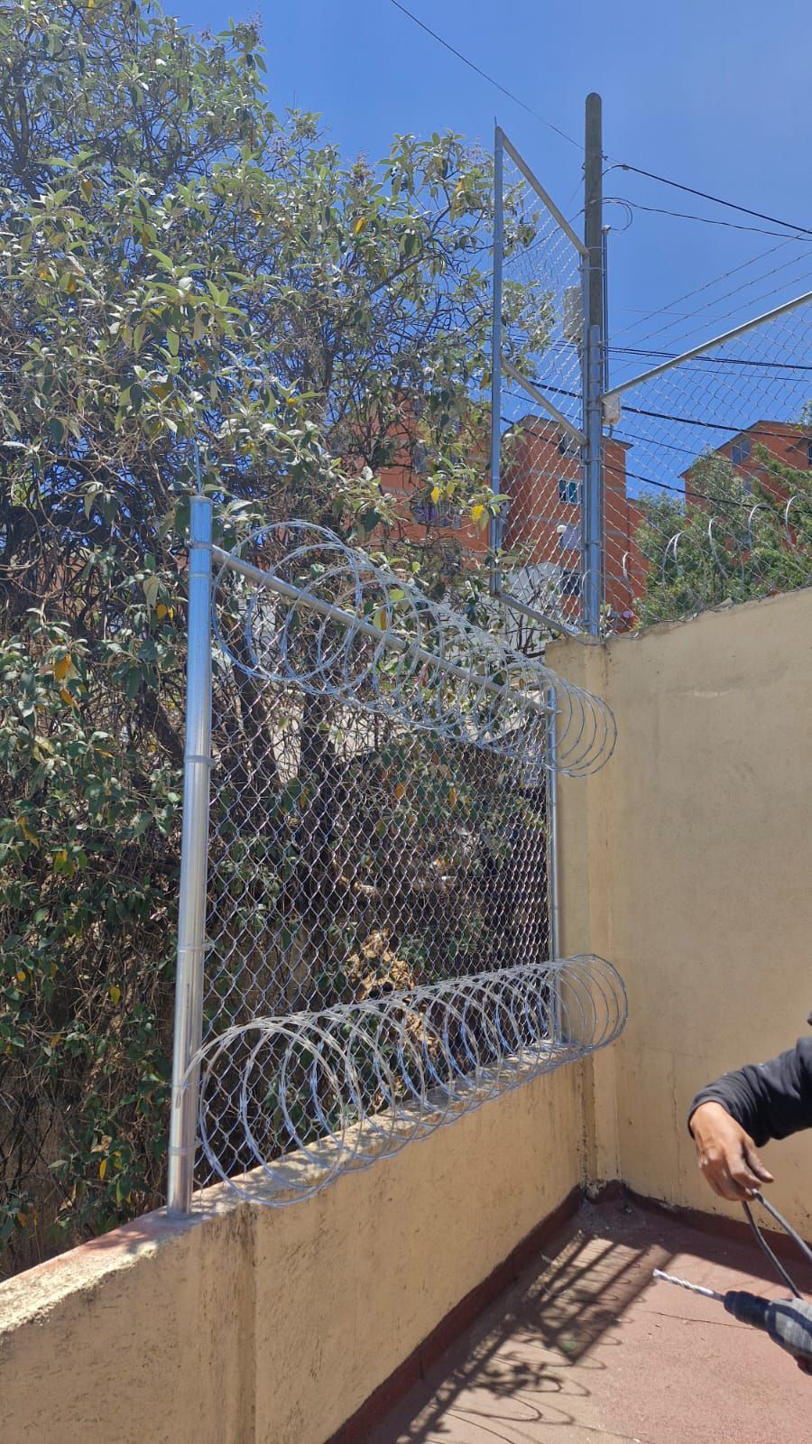 Una persona está parada junto a una cerca de alambre de púas.