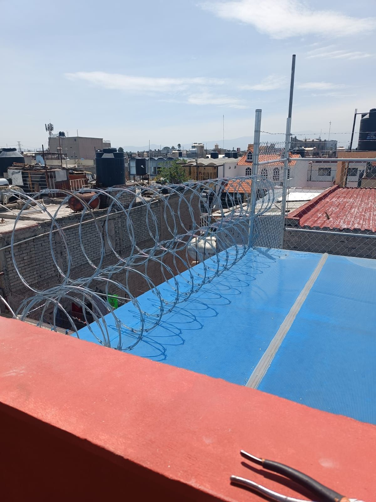 Se está instalando una valla de alambre de púas en el tejado de un edificio.