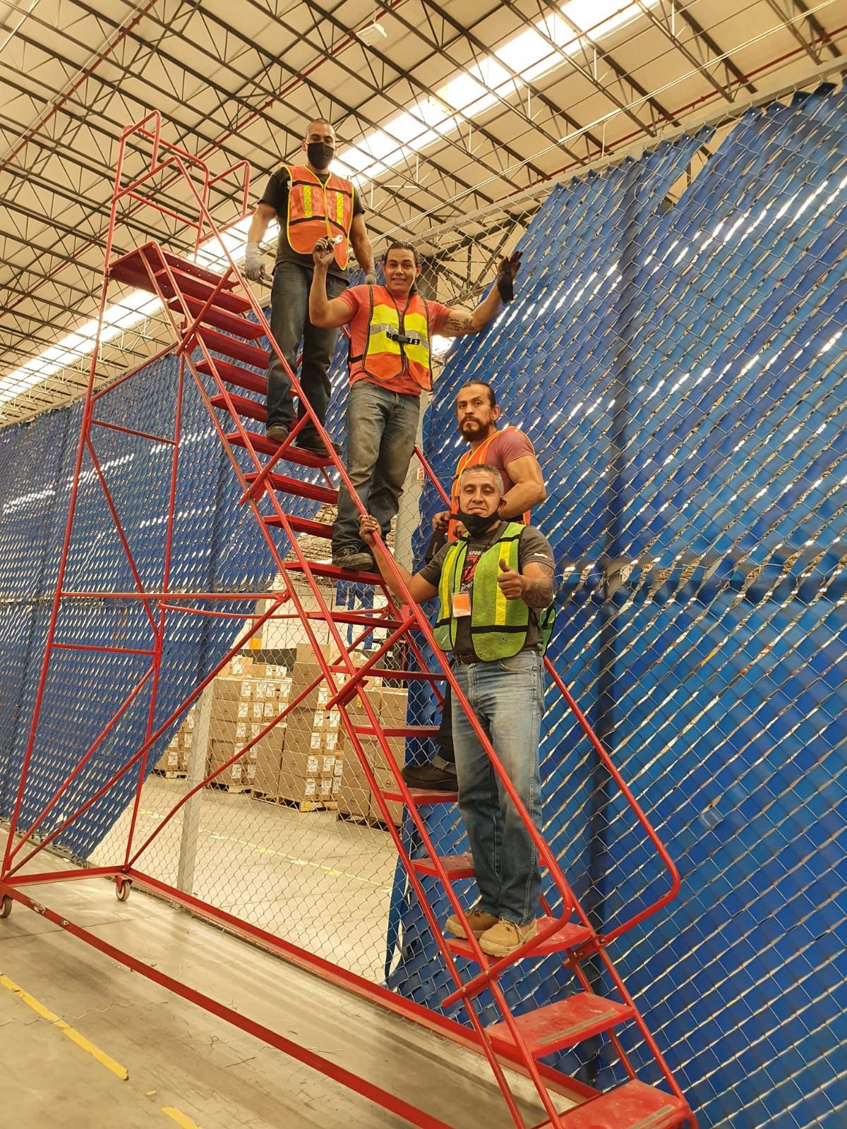 Un grupo de hombres está de pie en una escalera roja en un almacén.