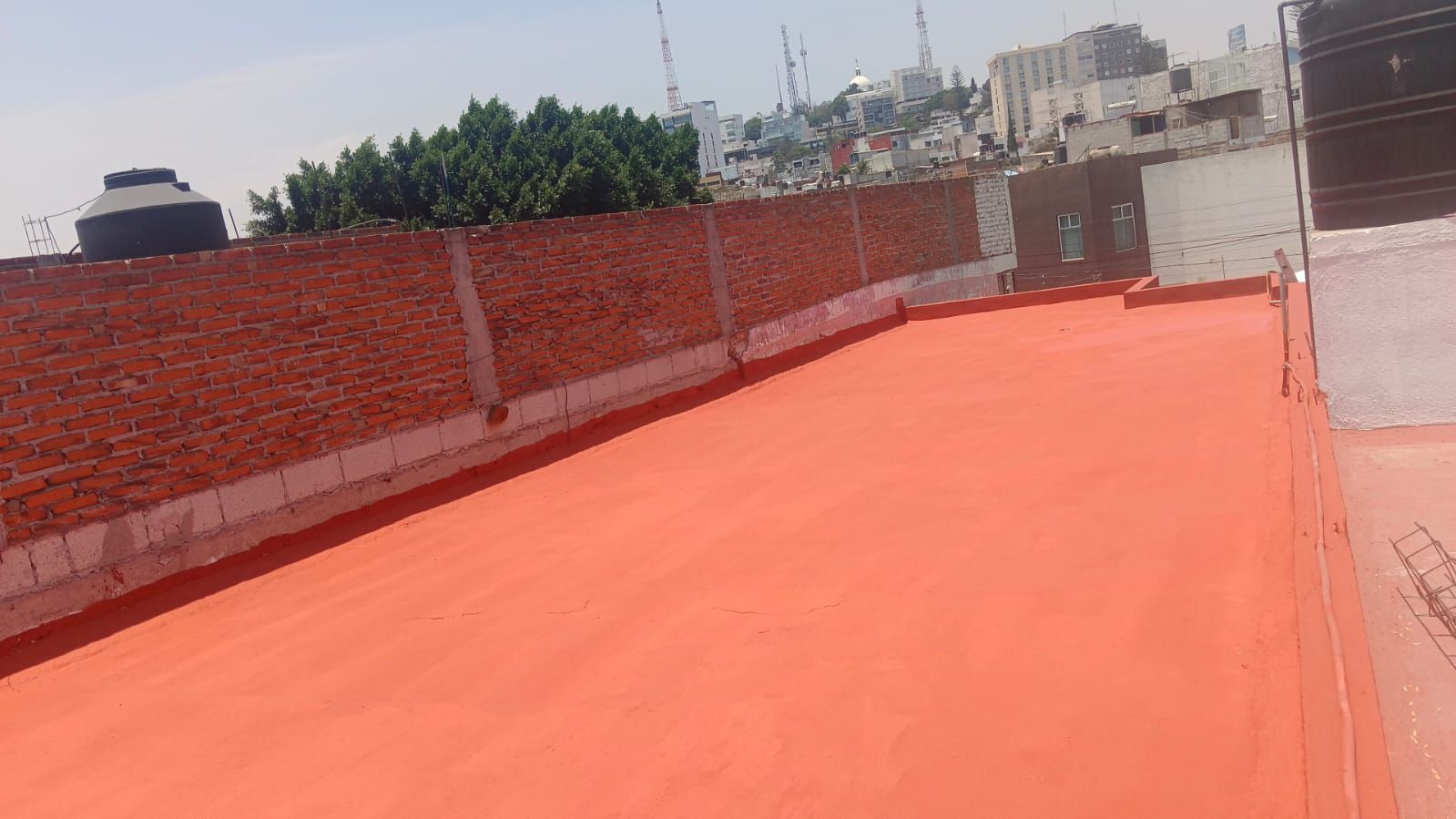 Un techo rojo con una pared de ladrillos al fondo.