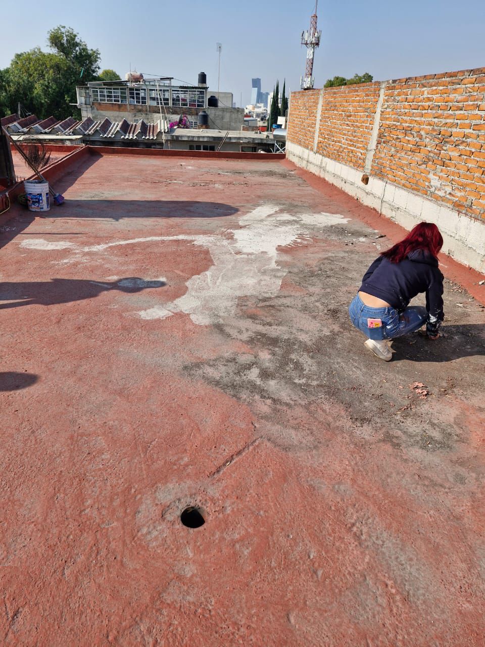 Una mujer está arrodillada sobre un techo con un agujero en él.