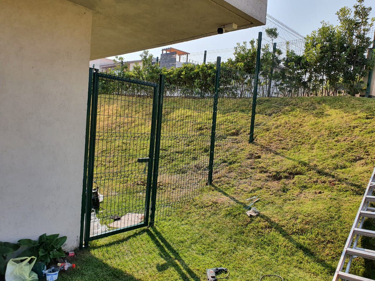 Una puerta verde está sentada en el césped al lado de una valla.