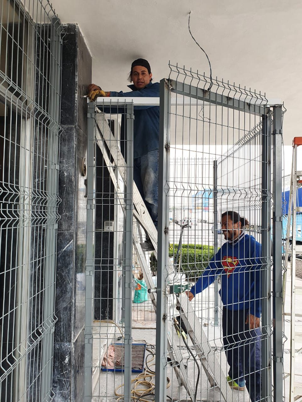 Un hombre está de pie en una escalera al lado de una valla.