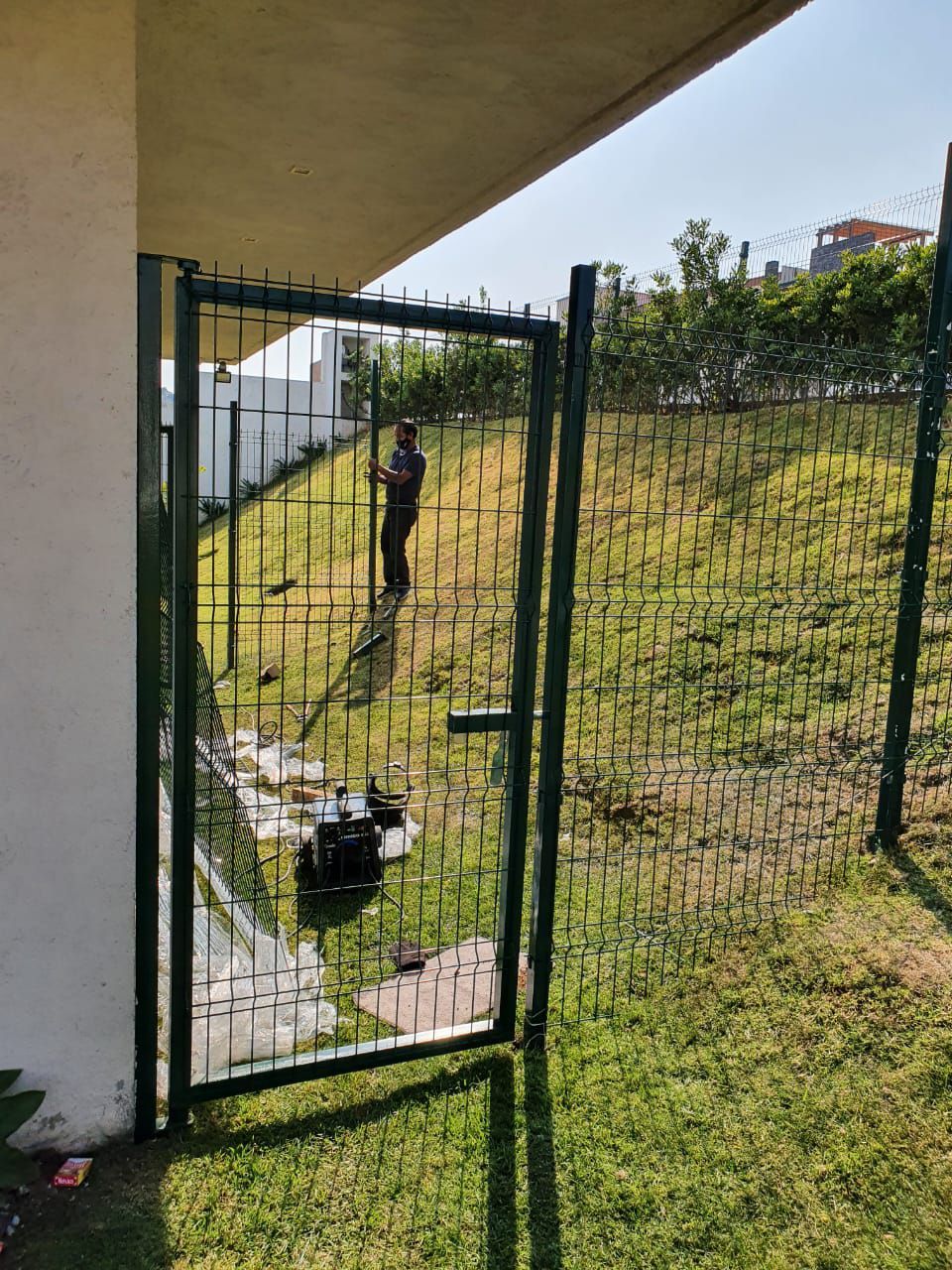 Una persona parada detrás de una valla con una puerta abierta