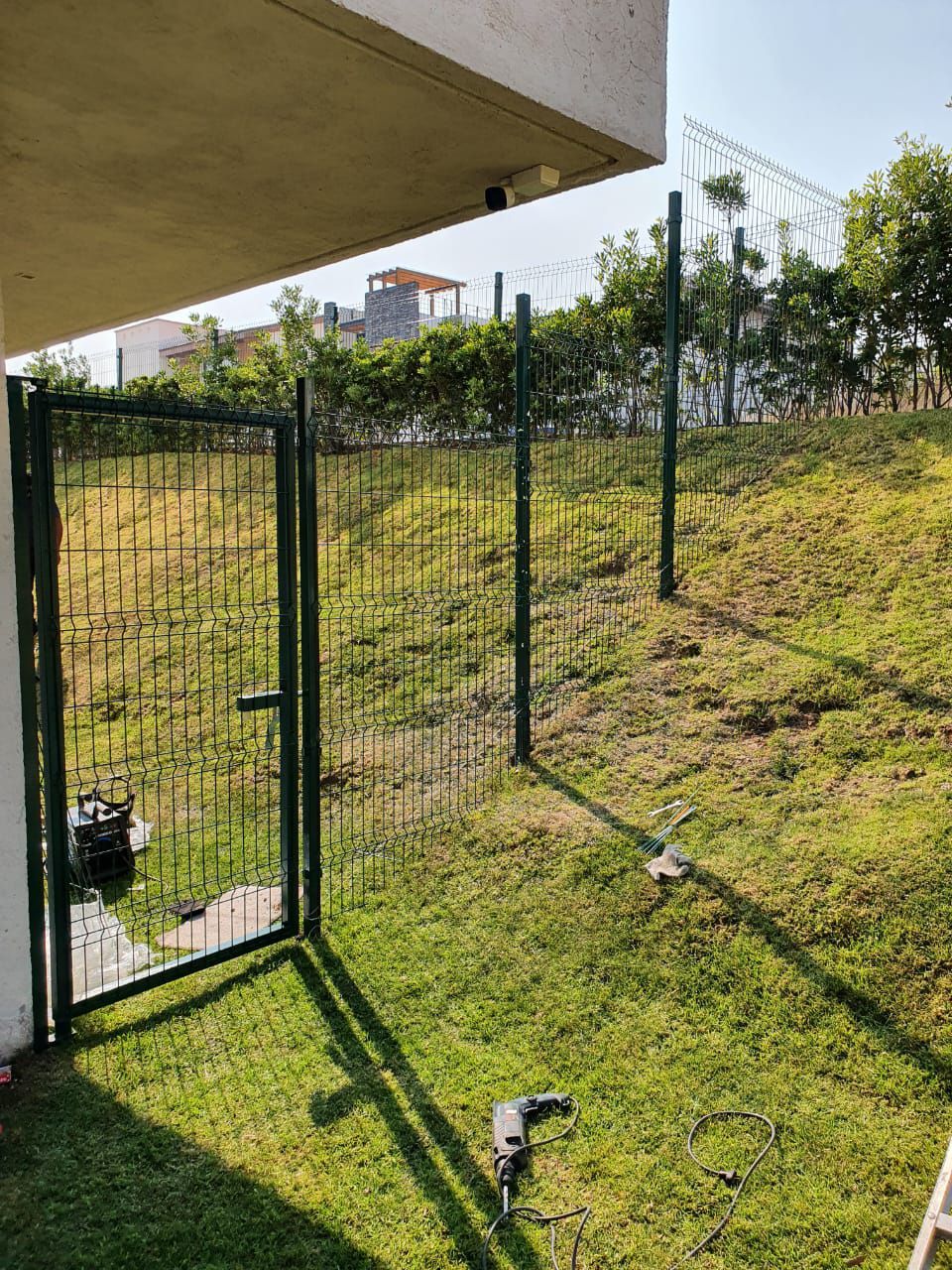 Una valla con una puerta en medio de un campo de hierba.