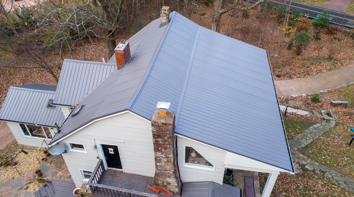 An aerial view of a house with a gray roof and a chimney.