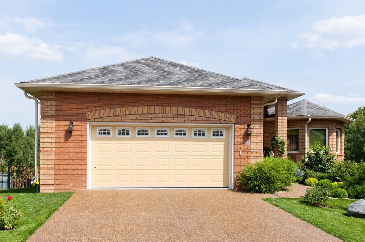 A brick house with a tan garage door and a driveway.