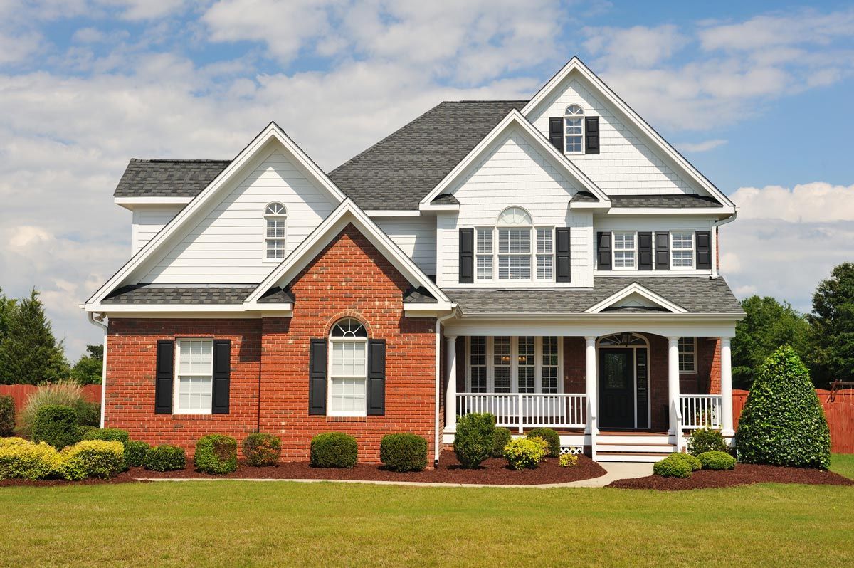 A large brick house with a white trim and black shutters