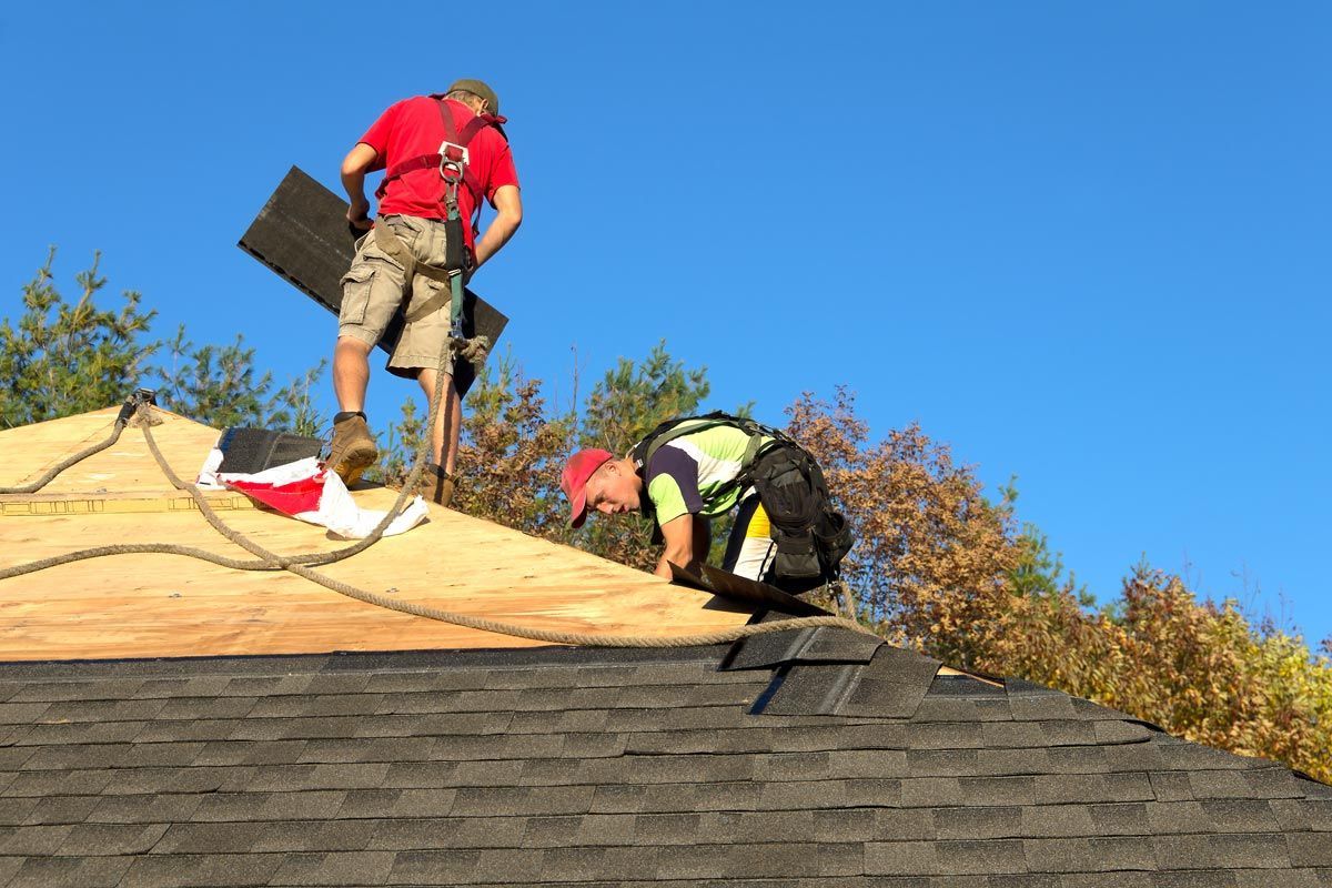 Two men are working on the roof of a house.